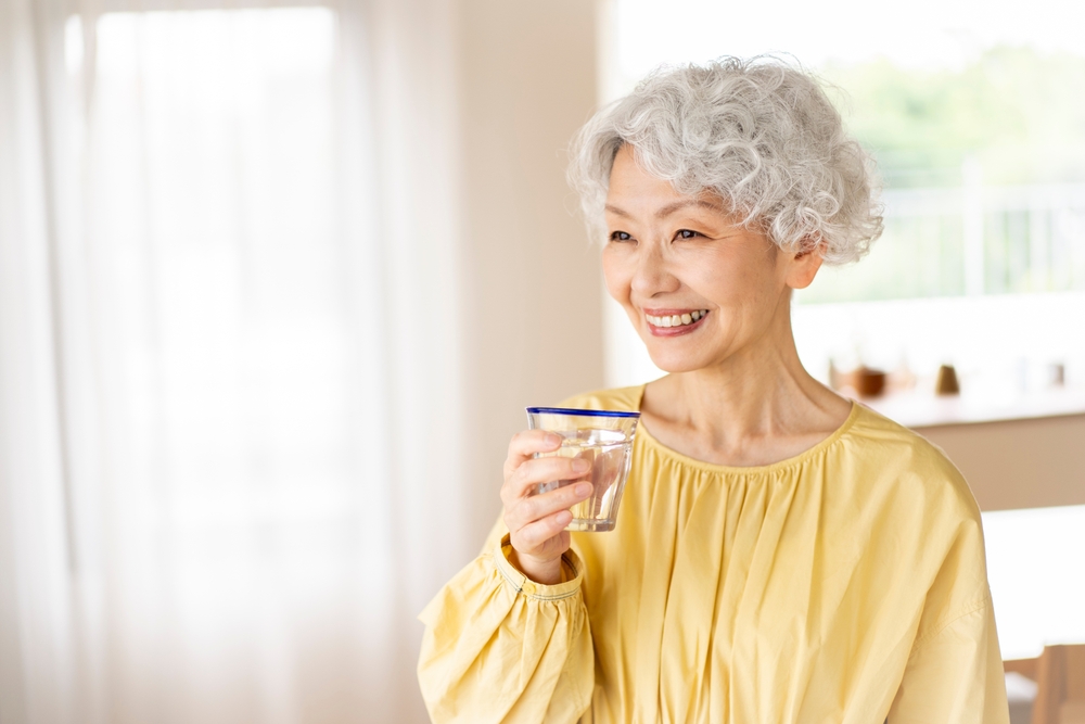 A senior woman is having a drink. 